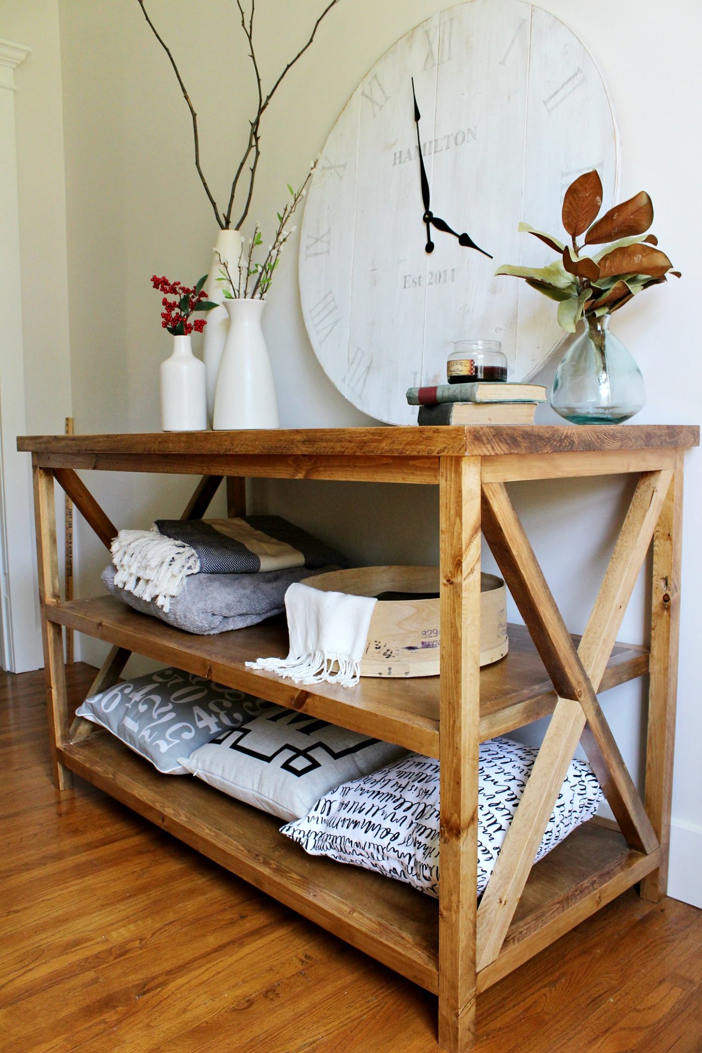 DIY X base console table with middle shelf for added storage against white wall