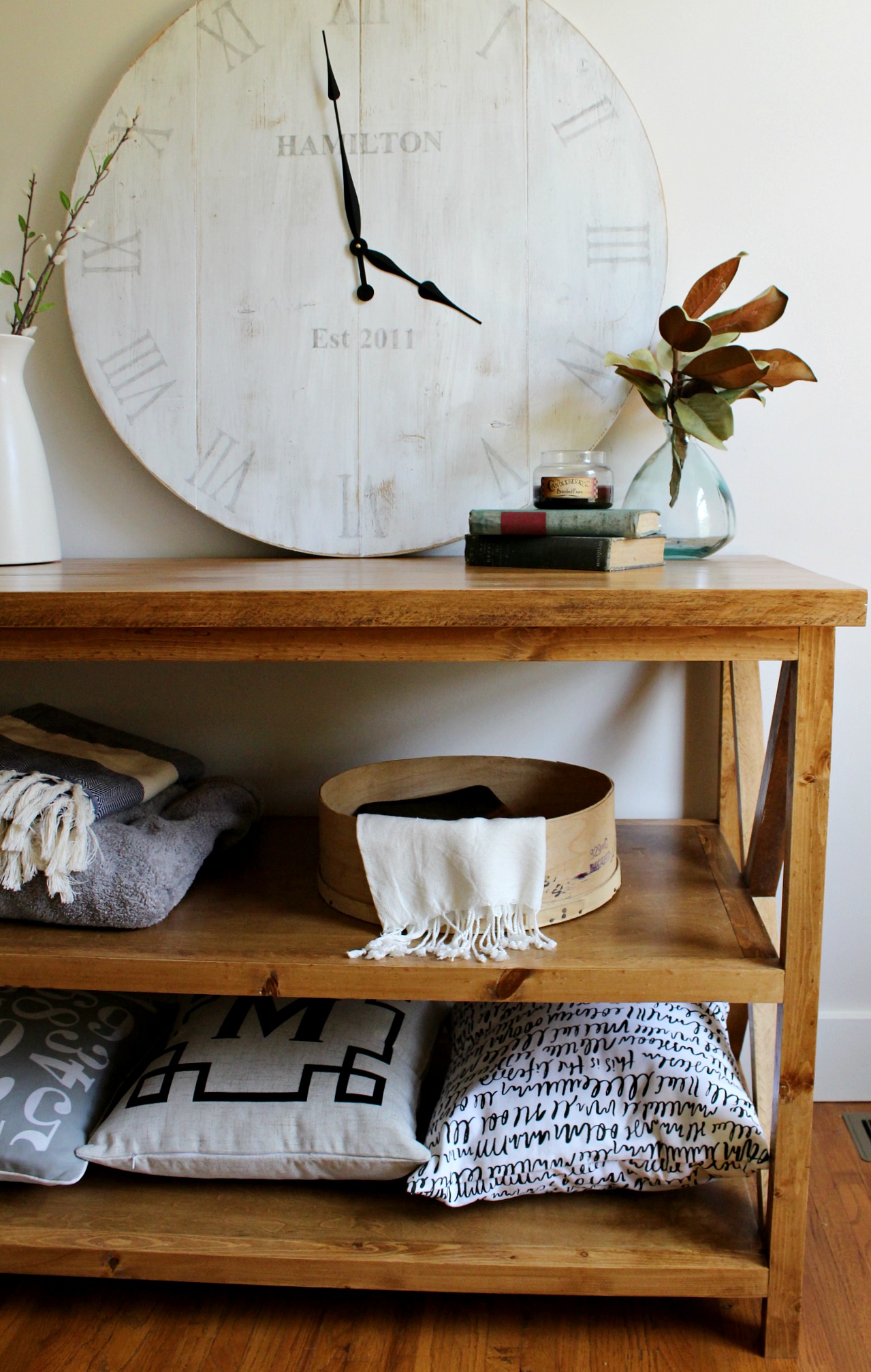 DIY X base console table with shelf completed and filled with blankets and books