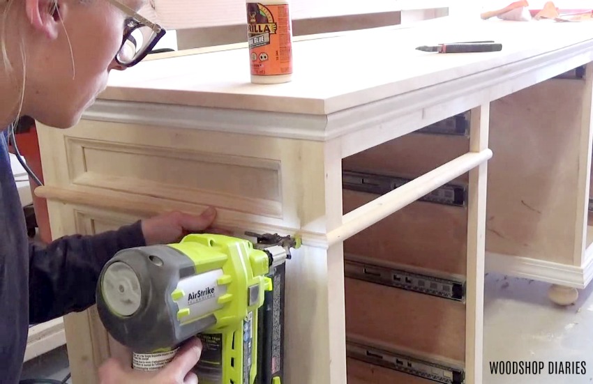 Close up of Shara Woodshop Diaries nailing half round molding around sides of home office desk project