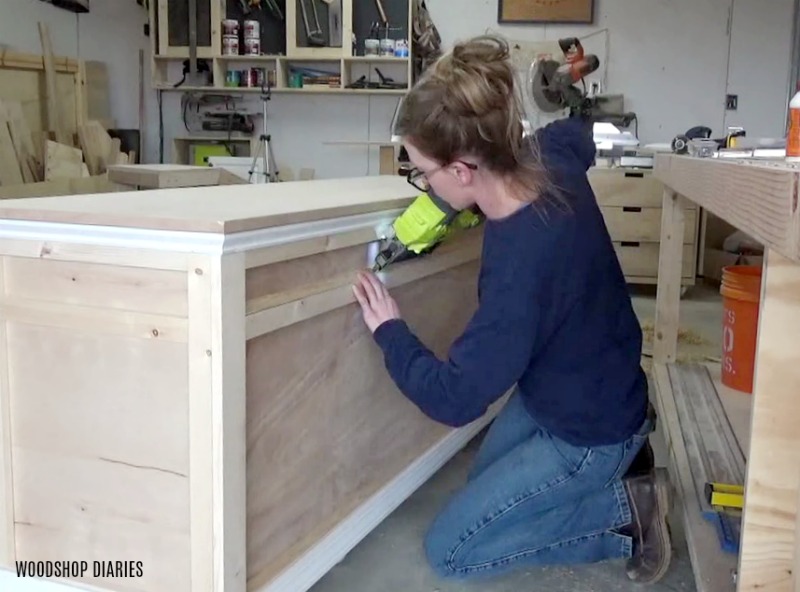 Shara Woodshop Diaries nailing cove molding around front of DIY storage desk project