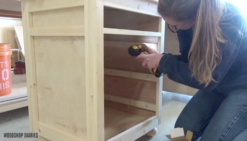 Shara Woodshop Diaries screwing spacer blocks into sides of desk cabinets