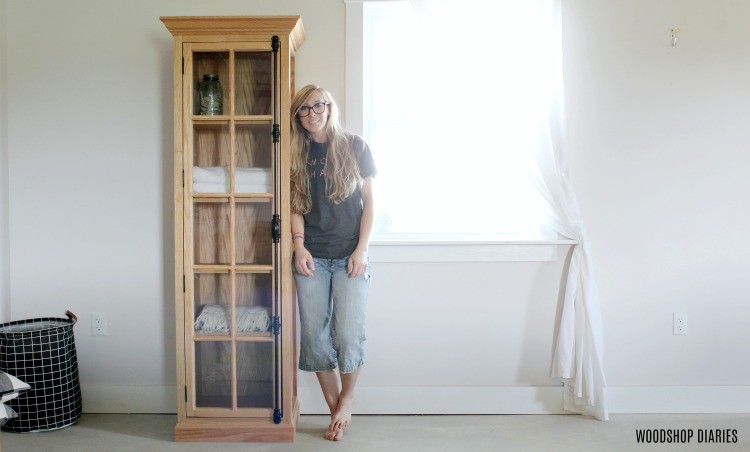Shara Woodshop Diaries standing next to DIY glass door linen cabinet with cremone bolt