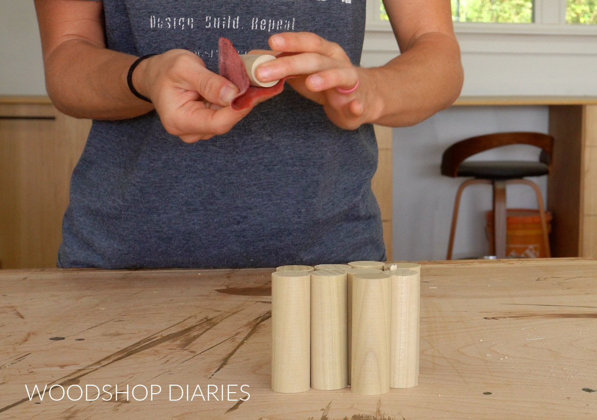 Close up of Shara Woodshop Diaries sanding dowels for rack pegs