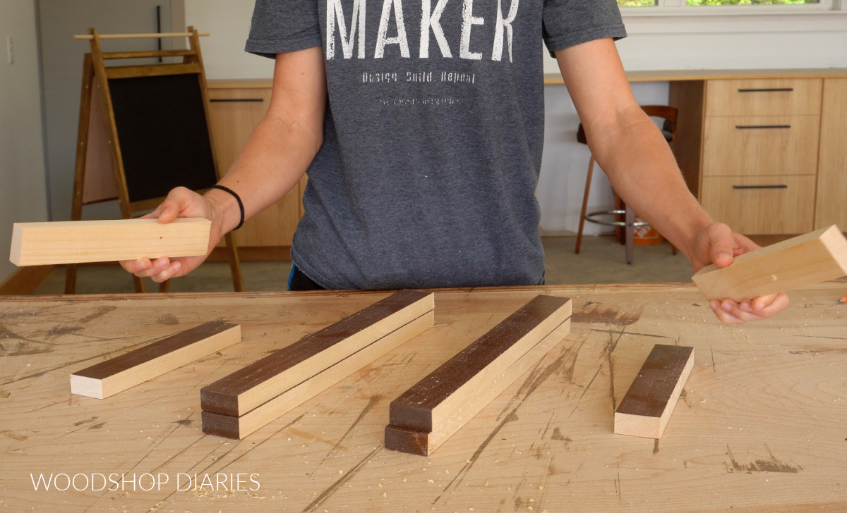 Shara Woodshop Diaries laying out accordion hat rack pieces on workbench