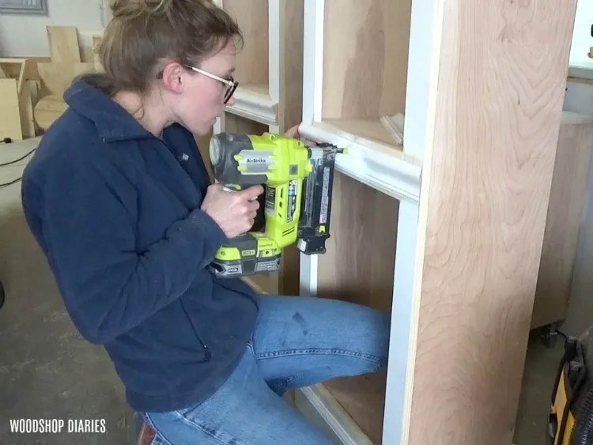 Shara Woodshop Diaries nailing chair rail molding onto side cabinets of entertainment center