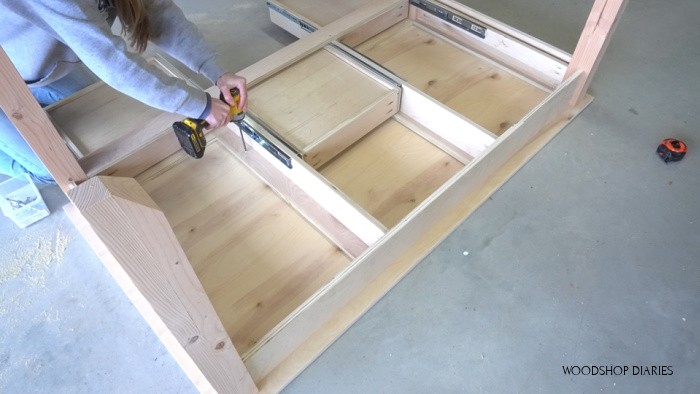 Desk flipped upside down screwing base to top through supports