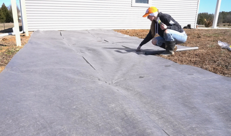 Shara using garden staples to secure landscape fabric in new garden area