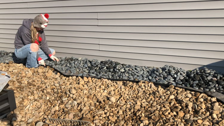 Shara spreading Mexican beach pebbles next to house