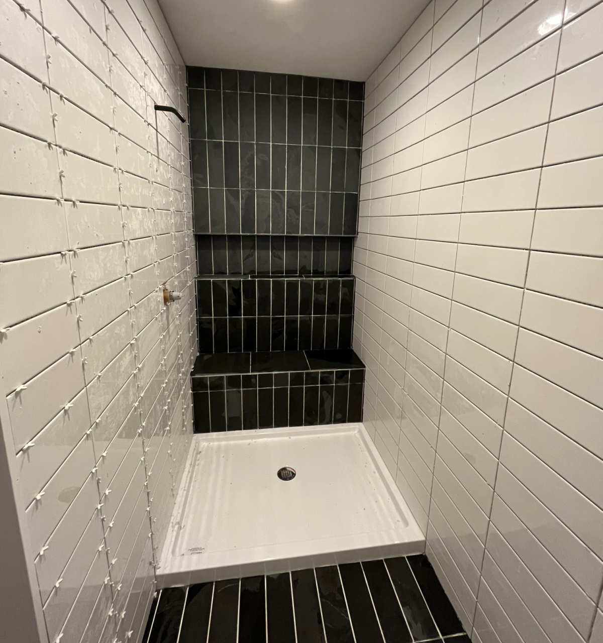 Dark slate and white subway tile shower  before grout is applied