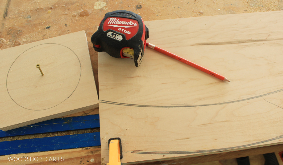 Tape measure sitting on plywood with circle drawn and radii drawn on workbench