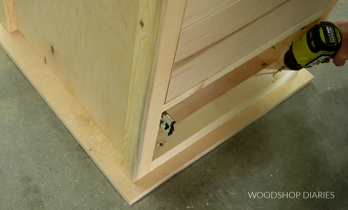 Driving screws through top frame to secure top panel of end table with drawers