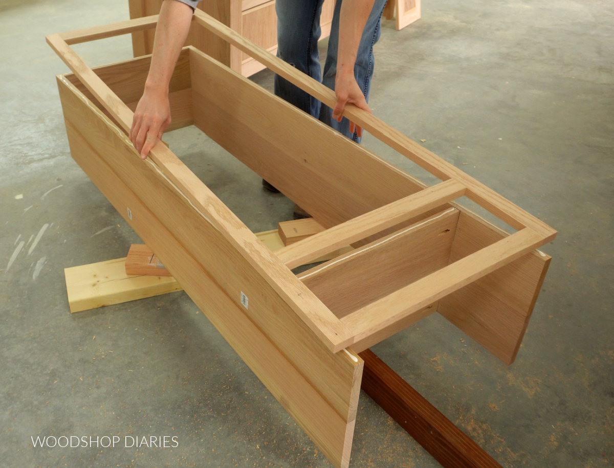 Shara Woodshop Diaries placing face frame onto cabinet box with glue
