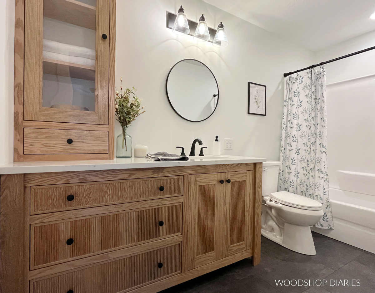 Modern bathroom with charcoal grey tile floor, wood vanity, and white walls