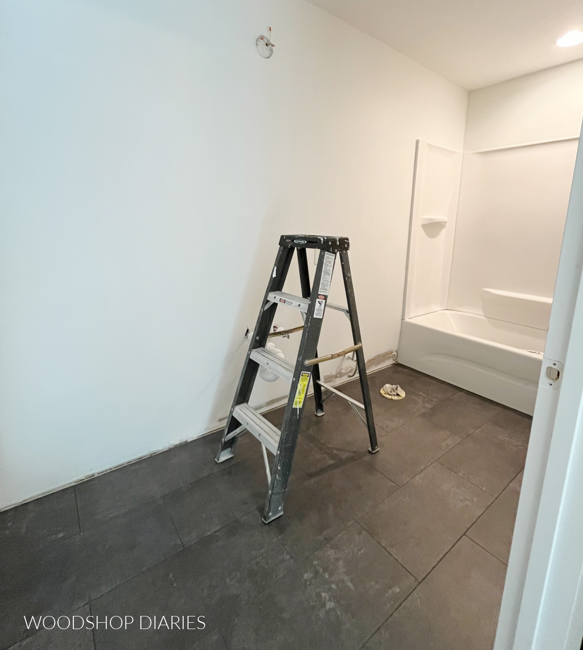 Small bathroom painted white with new vinyl tile floor laid in charcoal grey color