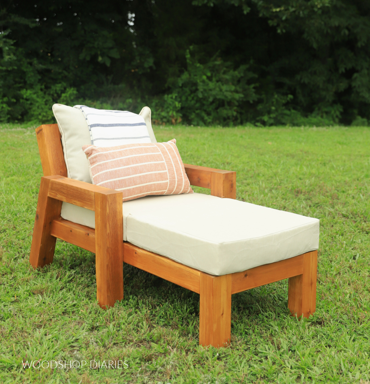 DIY outdoor wooden chaise lounge chair with chunky legs and beefy frame in grass with tan cushions