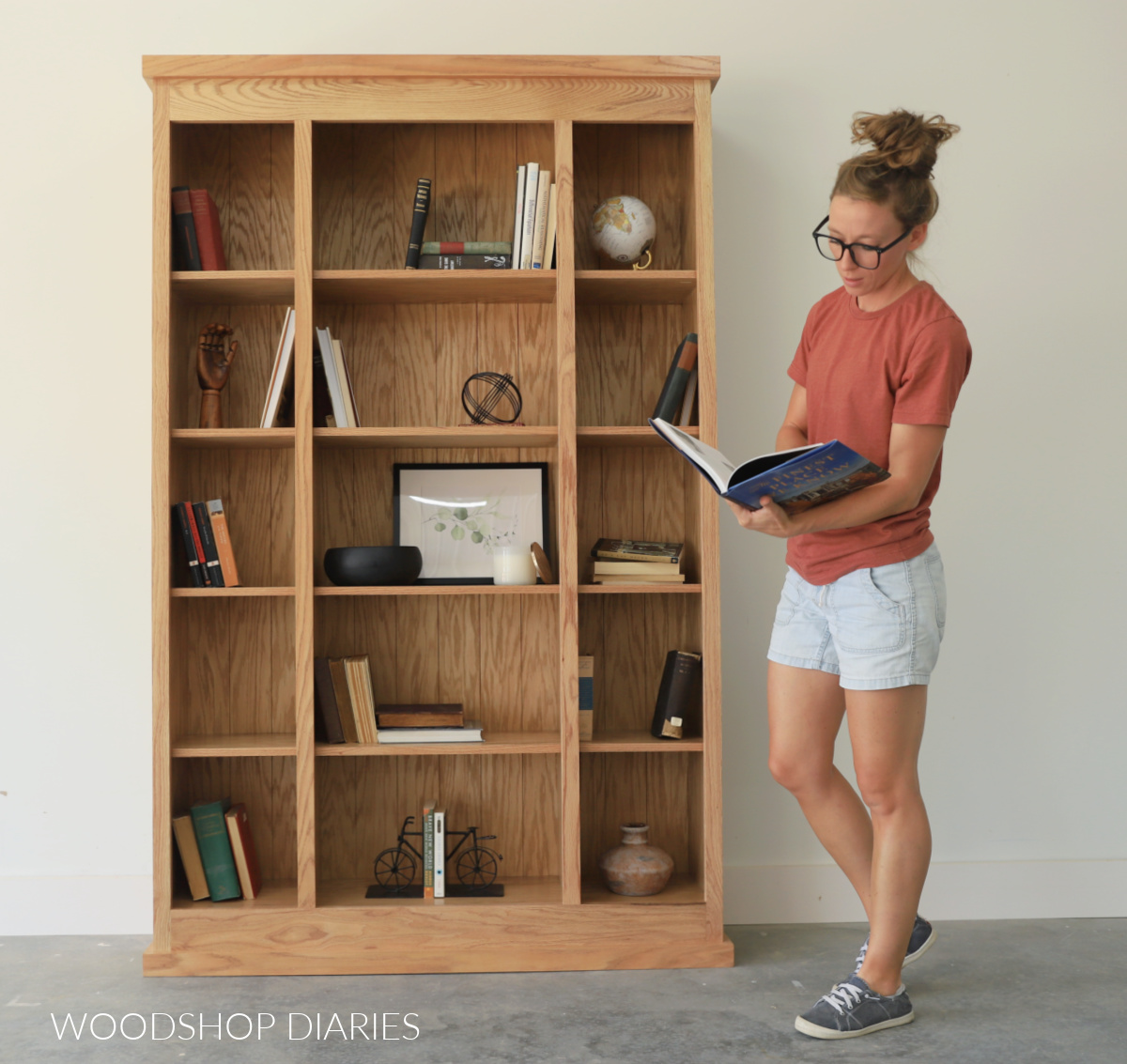 Shara Woodshop Diaries standing next to classic DIY bookcase reading a book