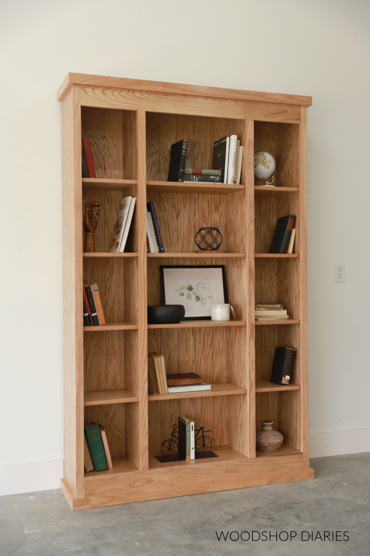 Finished red oak bookcase with books and decor on shelves