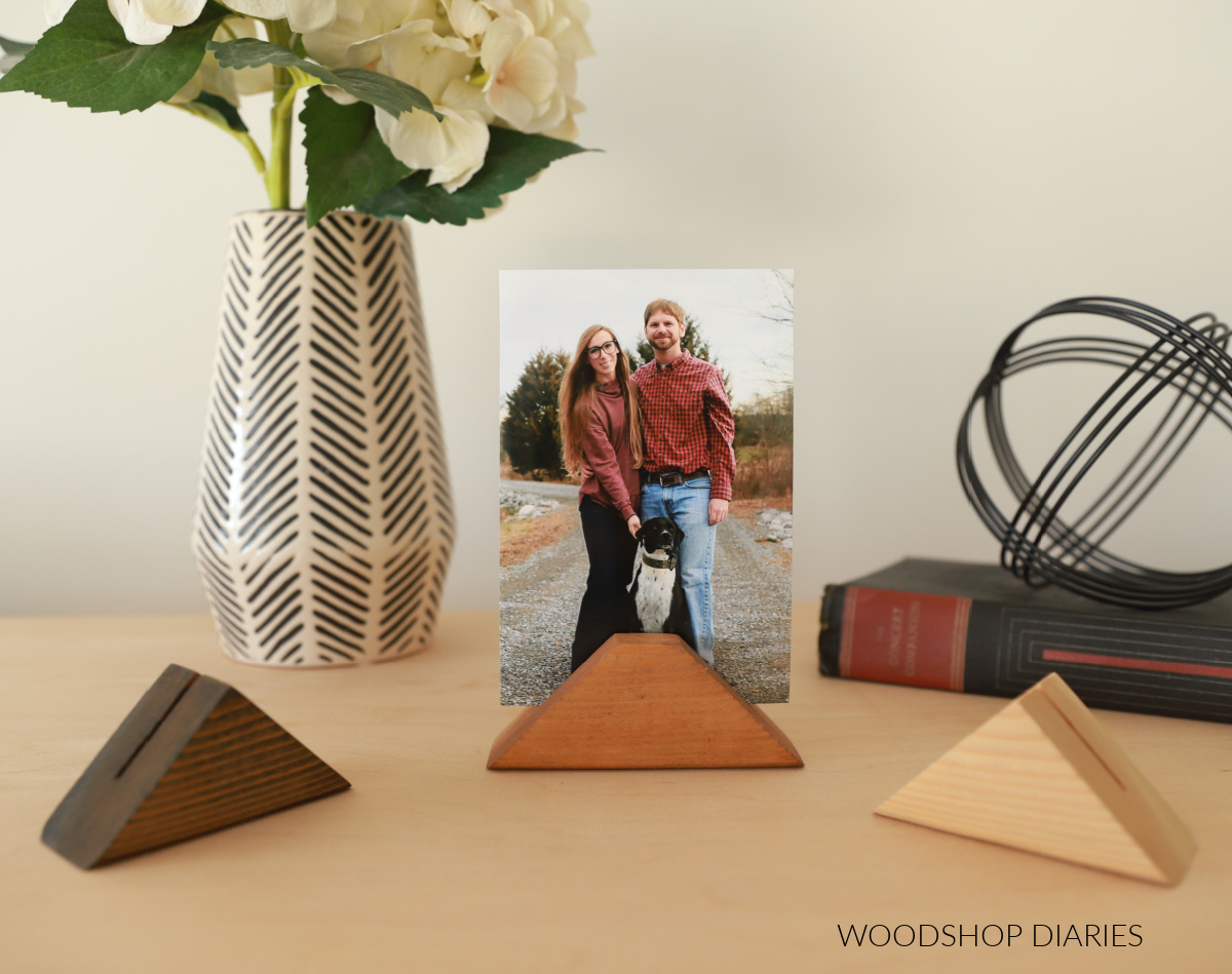 three different color stained card holder blocks on wood top with photo in one