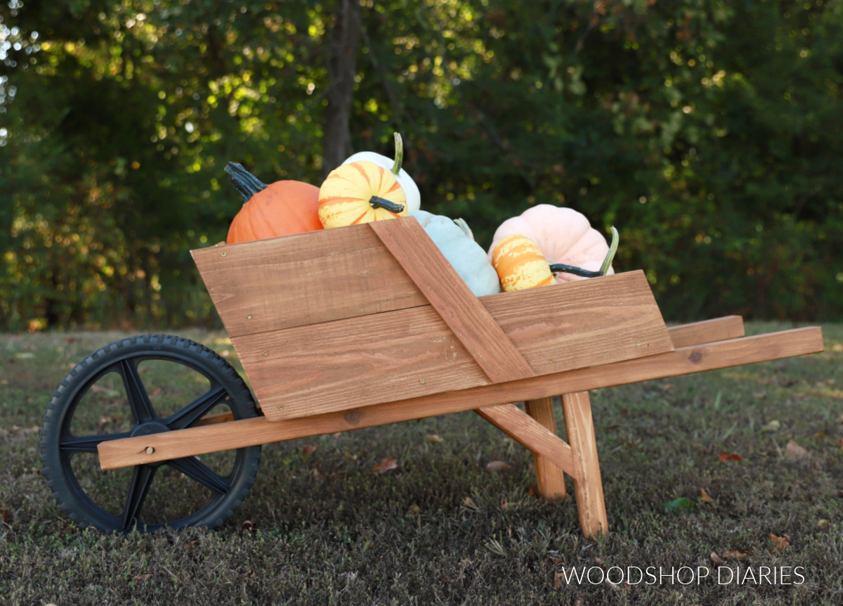 Completed decorative wheelbarrow filled with pumpkins in yard