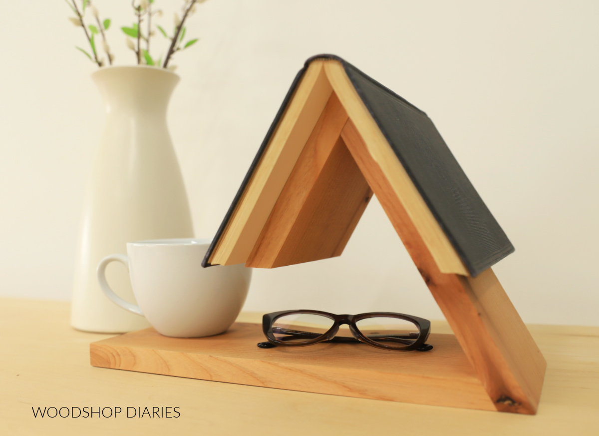 DIY modern wooden book holder made from alder wood with book on top, glasses and mug on bottom