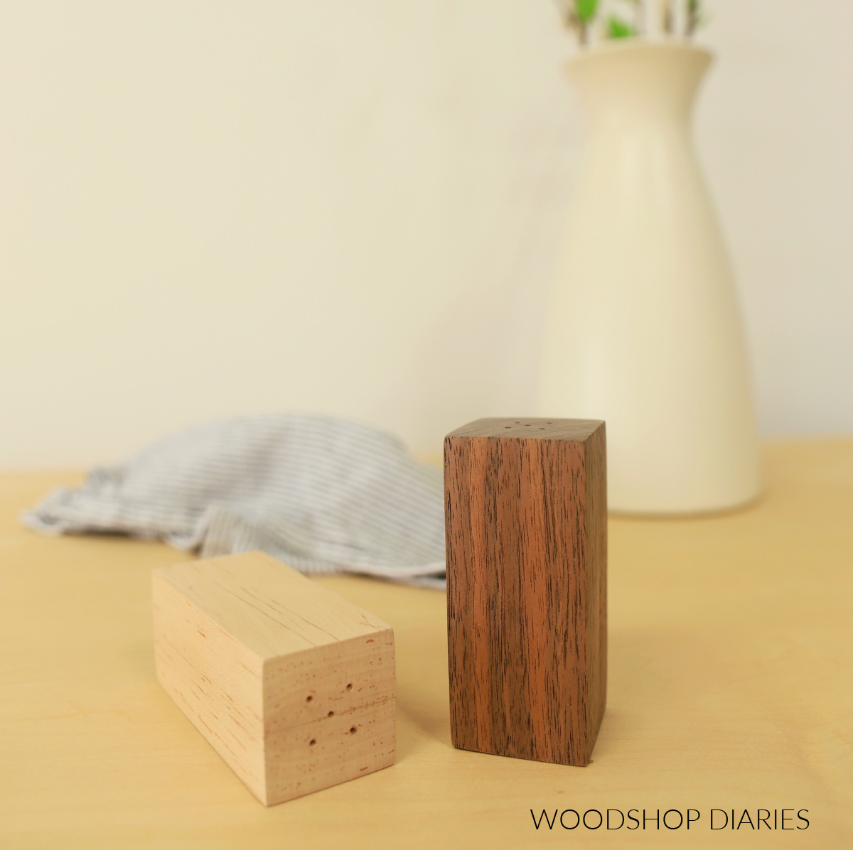 walnut and maple wooden salt and pepper shakers on wood table top--salt shaker turned on its side