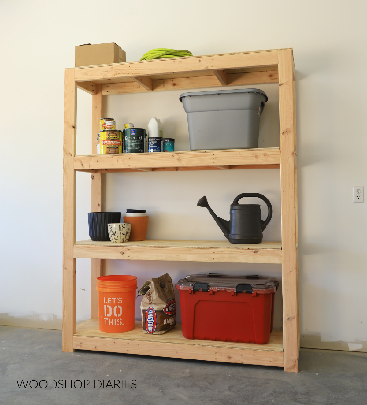DIY Wooden 4 tier garage shelf with totes, planters, buckets and cans of finish on the shelves