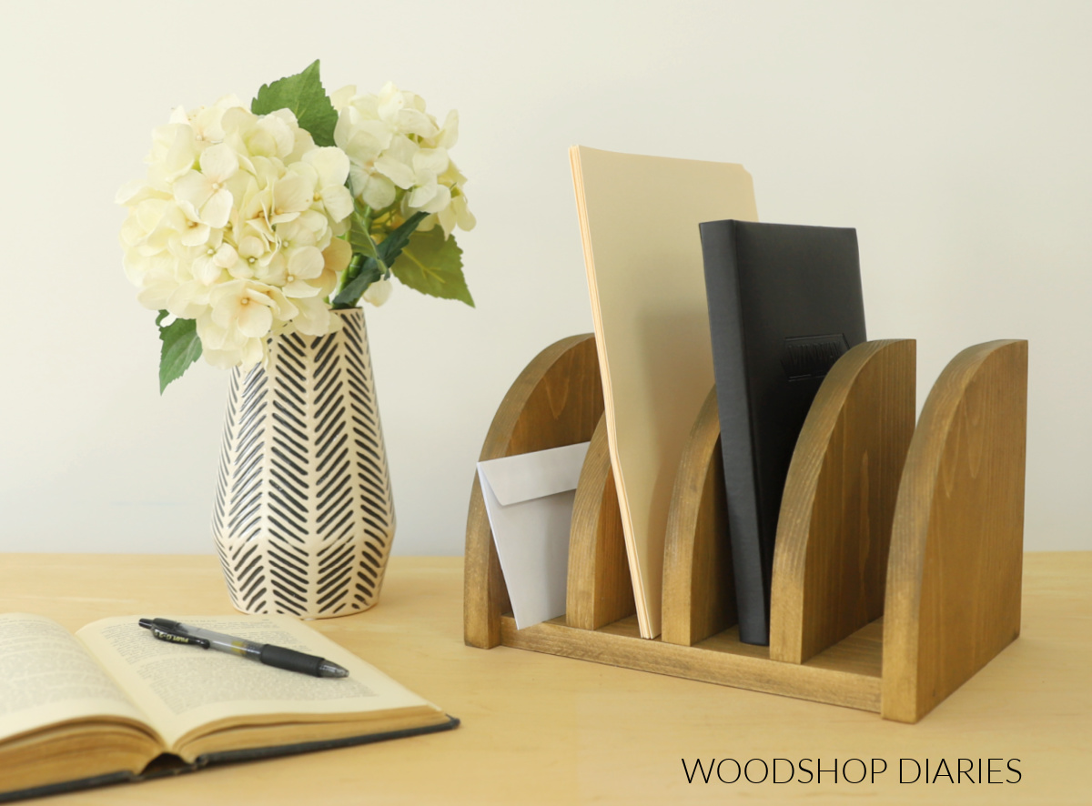DIY desk organizer with file folders and notebook on desk with flowers in vase