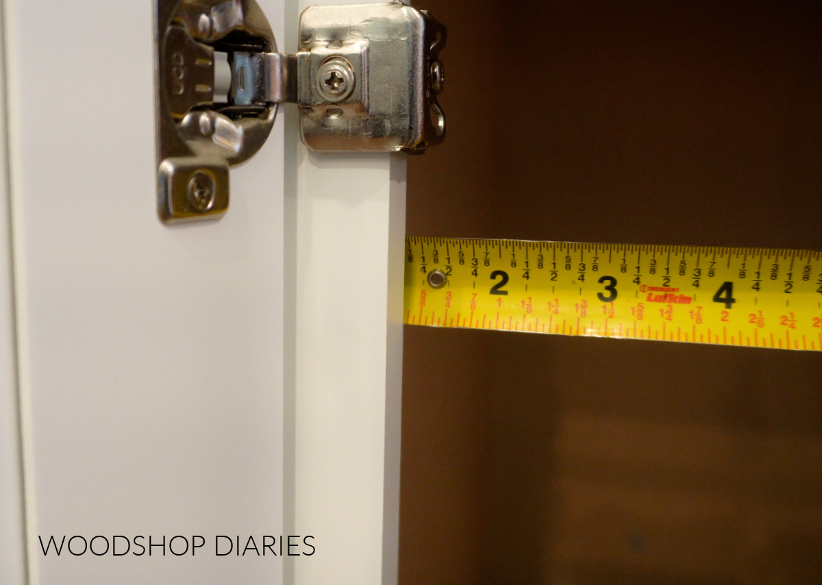 Using a tape measure to measure face frame overhang on inside of cabinet box