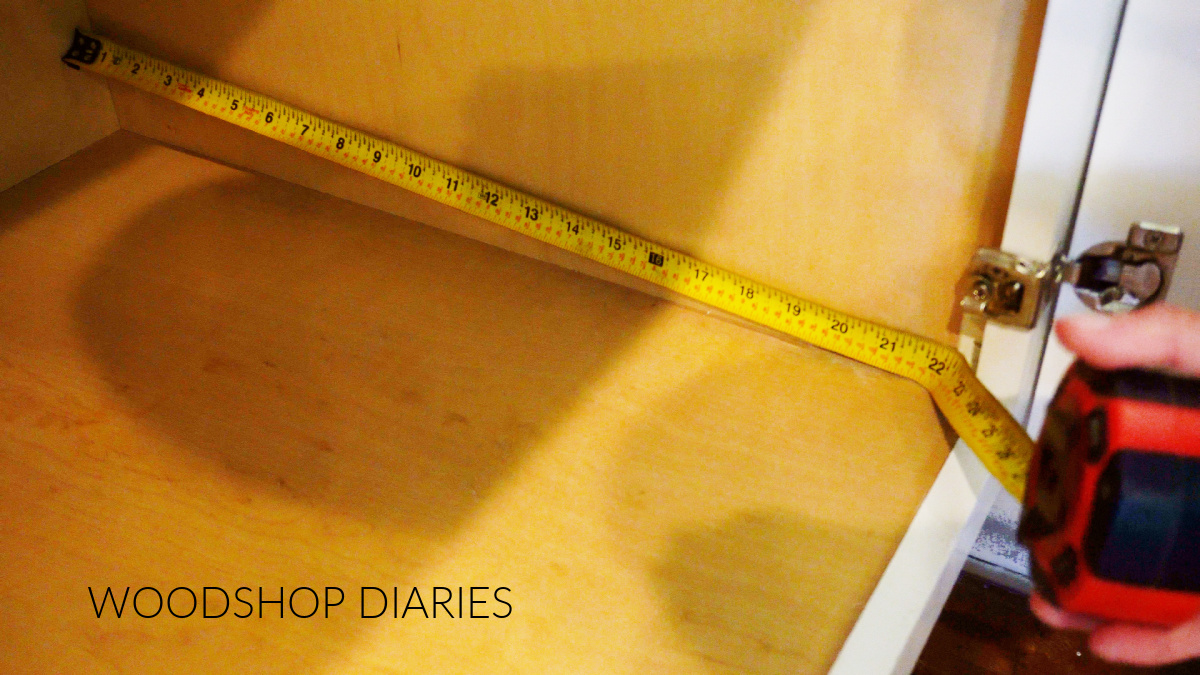 Using a tape measure to measure the cabinet depth front to back