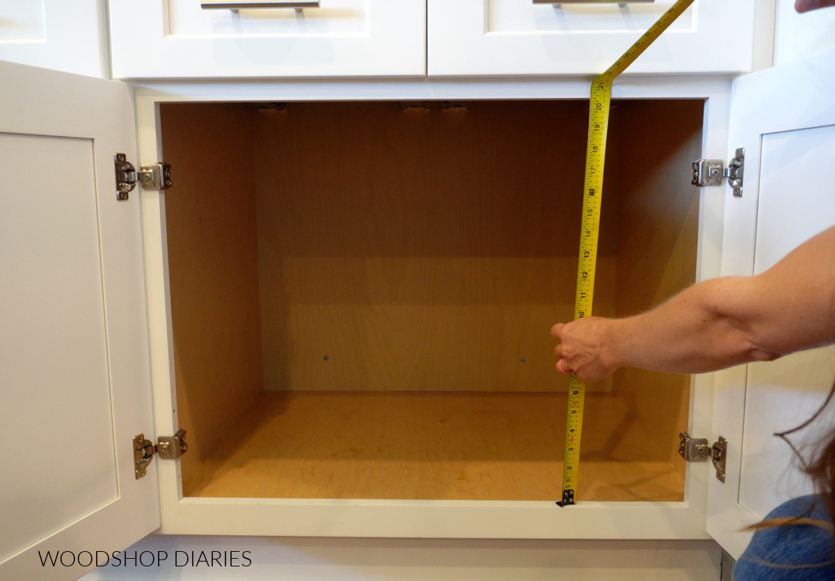 Using tape measure to measure height of base cabinet opening