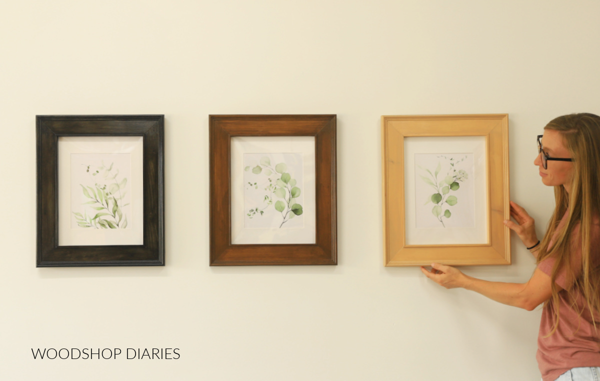 Shara Woodshop Diaries hanging wooden DIY picture frames on the wall--three different color frames with greenery prints inside