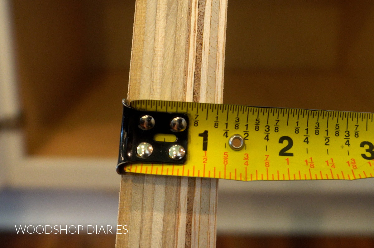 Close up of thickness of plywood spacer block measured with tape measure