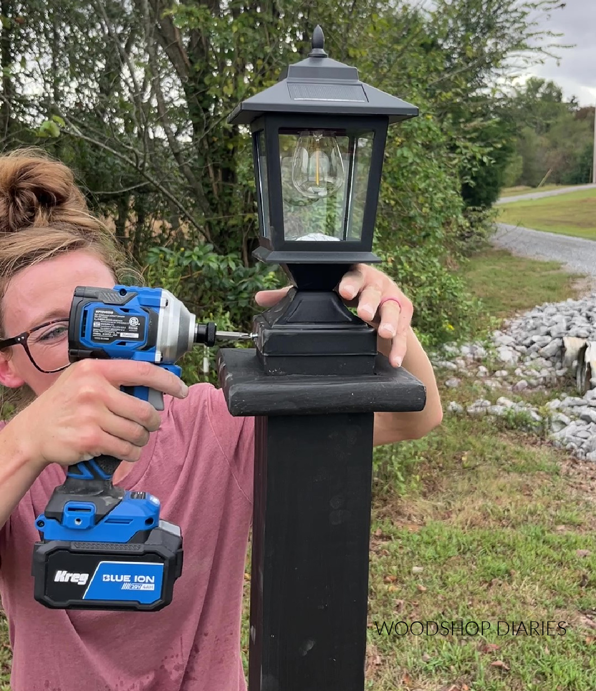 Close up of attaching solar lantern to top of wooden lamp post