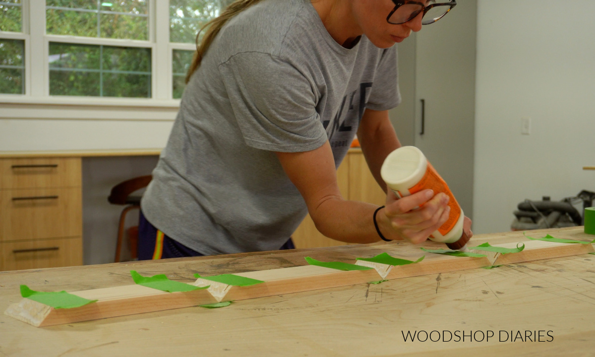 Shara Woodshop Diaries applying wood glue to board ends to assemble shadow box on workbench