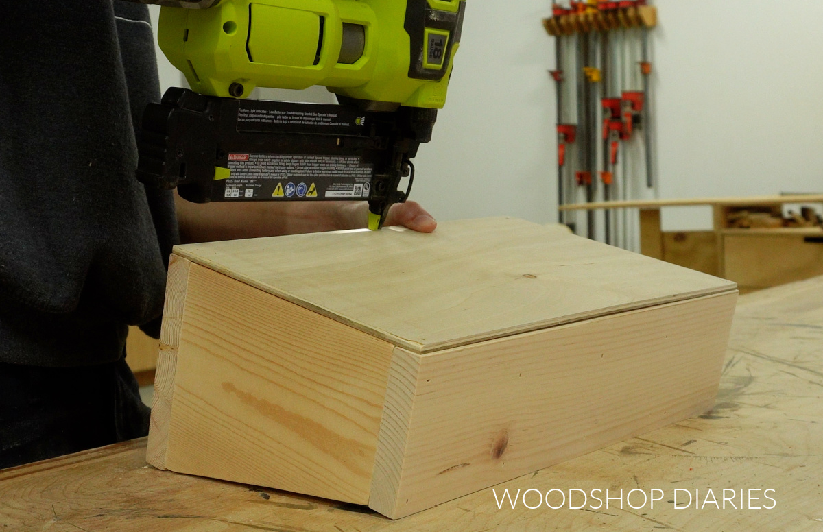 Close up of brad nailing ¼" plywood panel onto bottom of wooden caddy