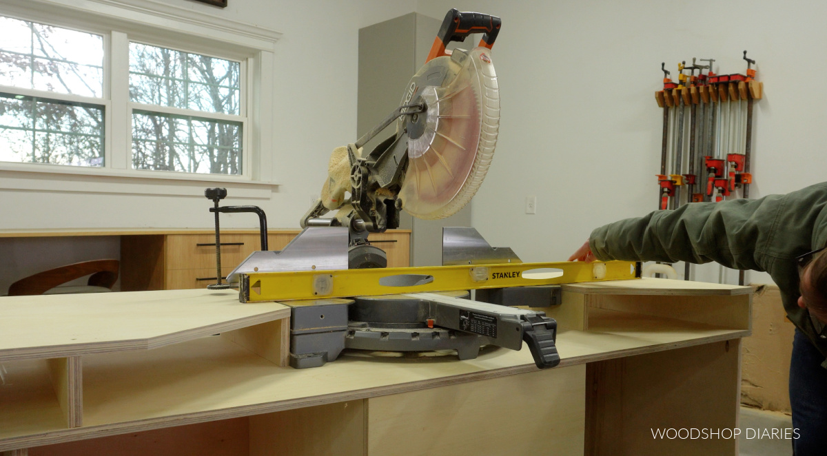 Shara Woodshop Diaries checking miter saw level to supports on mobile miter saw stand