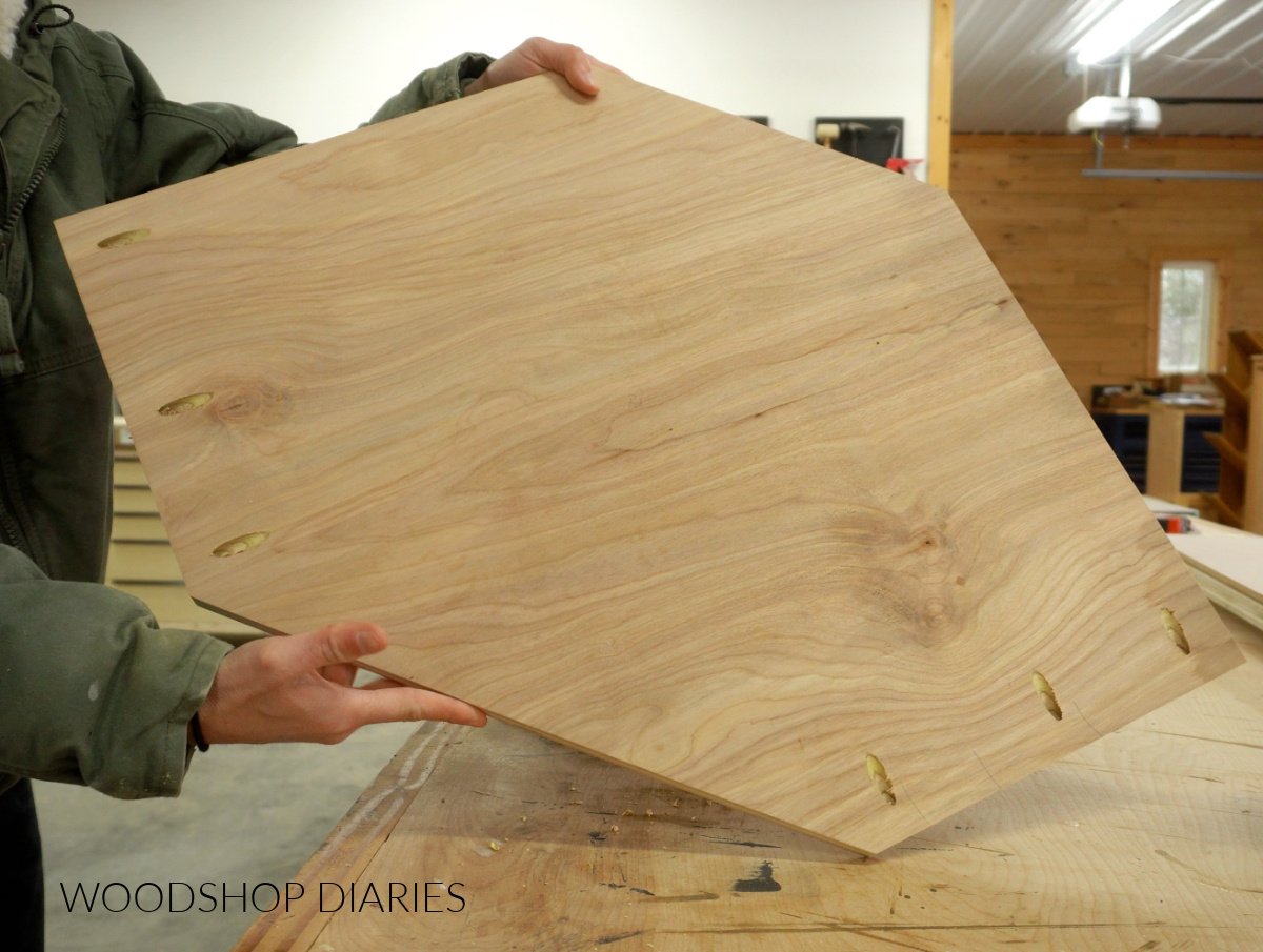 Bottom panel of DIY corner wall cabinet with pocket holes drilled for assembly