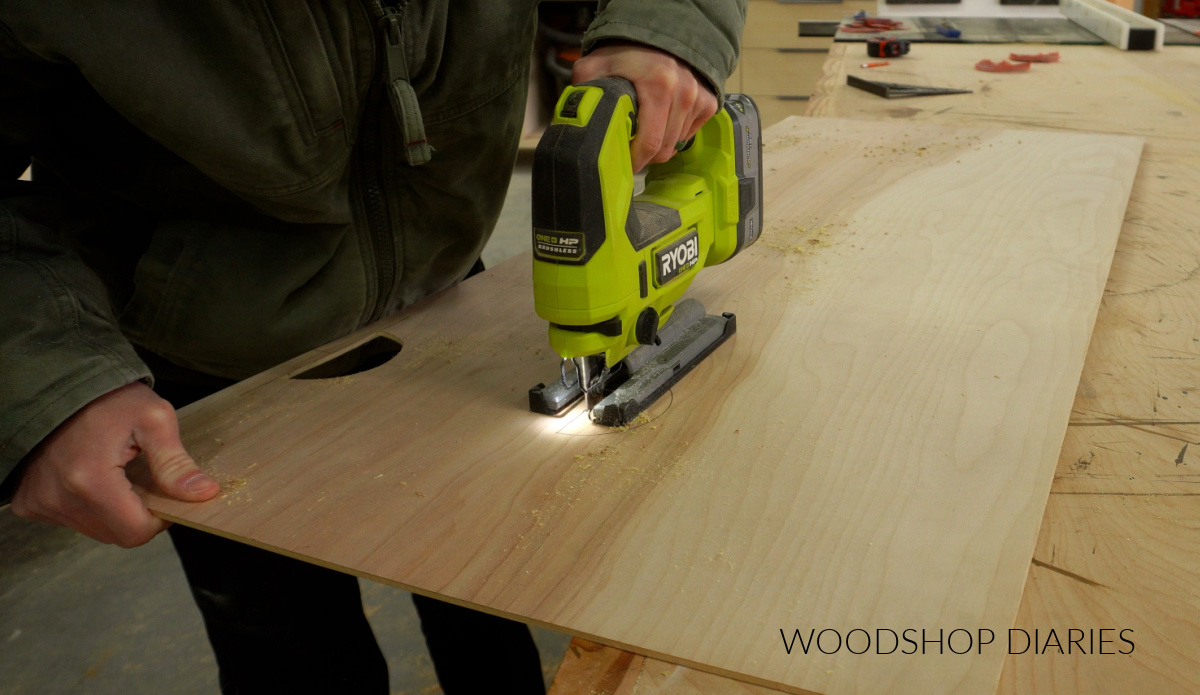 Shara Woodshop Diaries using jig saw to cut out sections of back panel to run cables and cords in TV stand