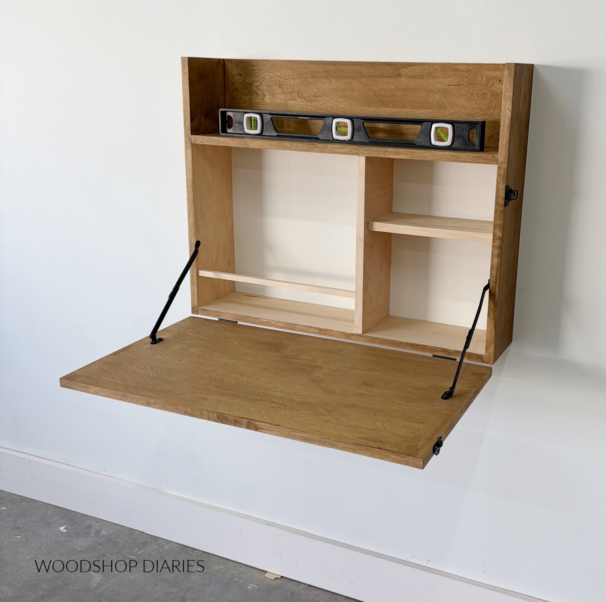 DIY Murphy desk hung on wall with fold down panel open and level sitting on top