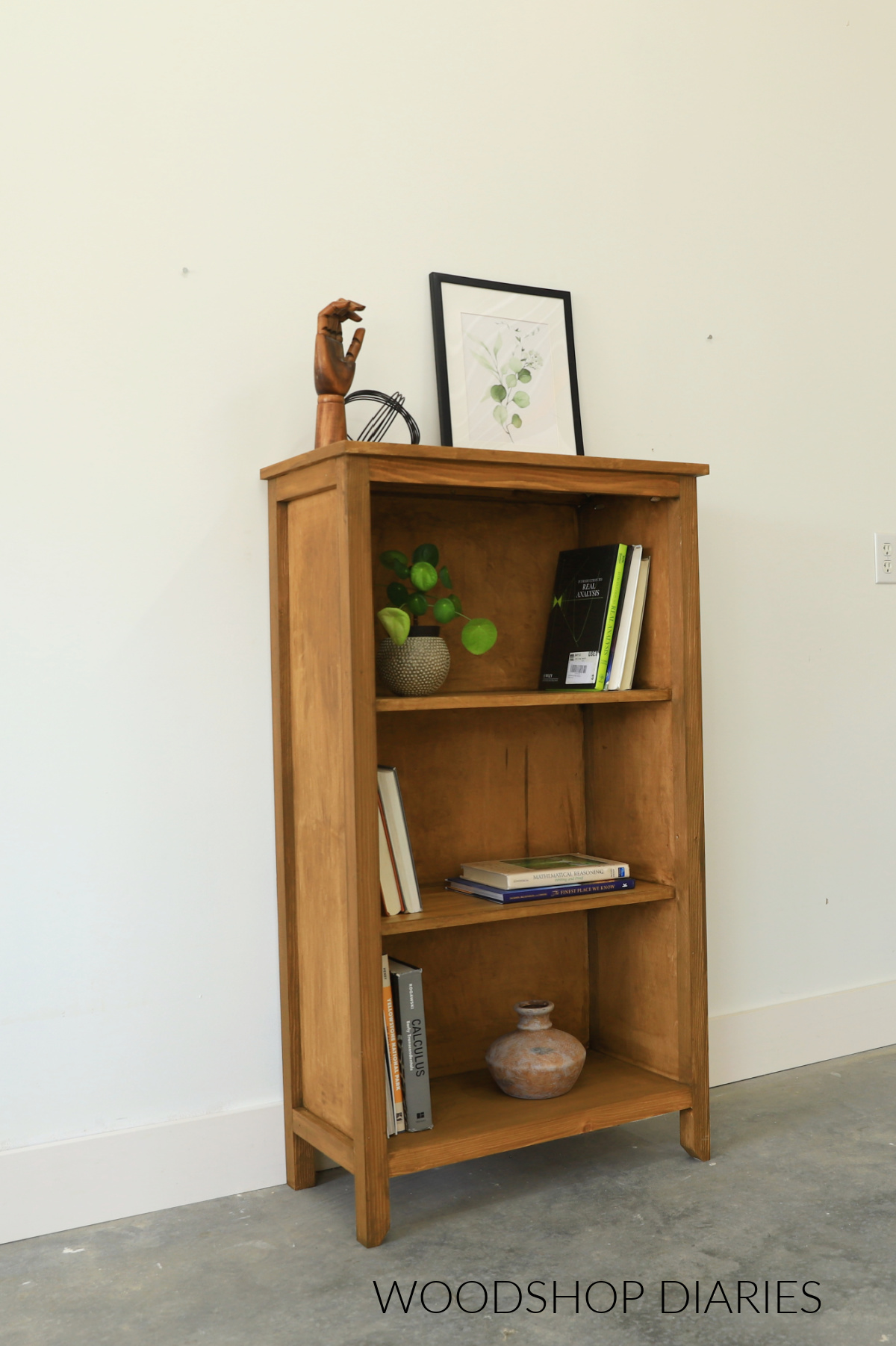 Completed wooden DIY small bookcase with three stationary shelves stained brown