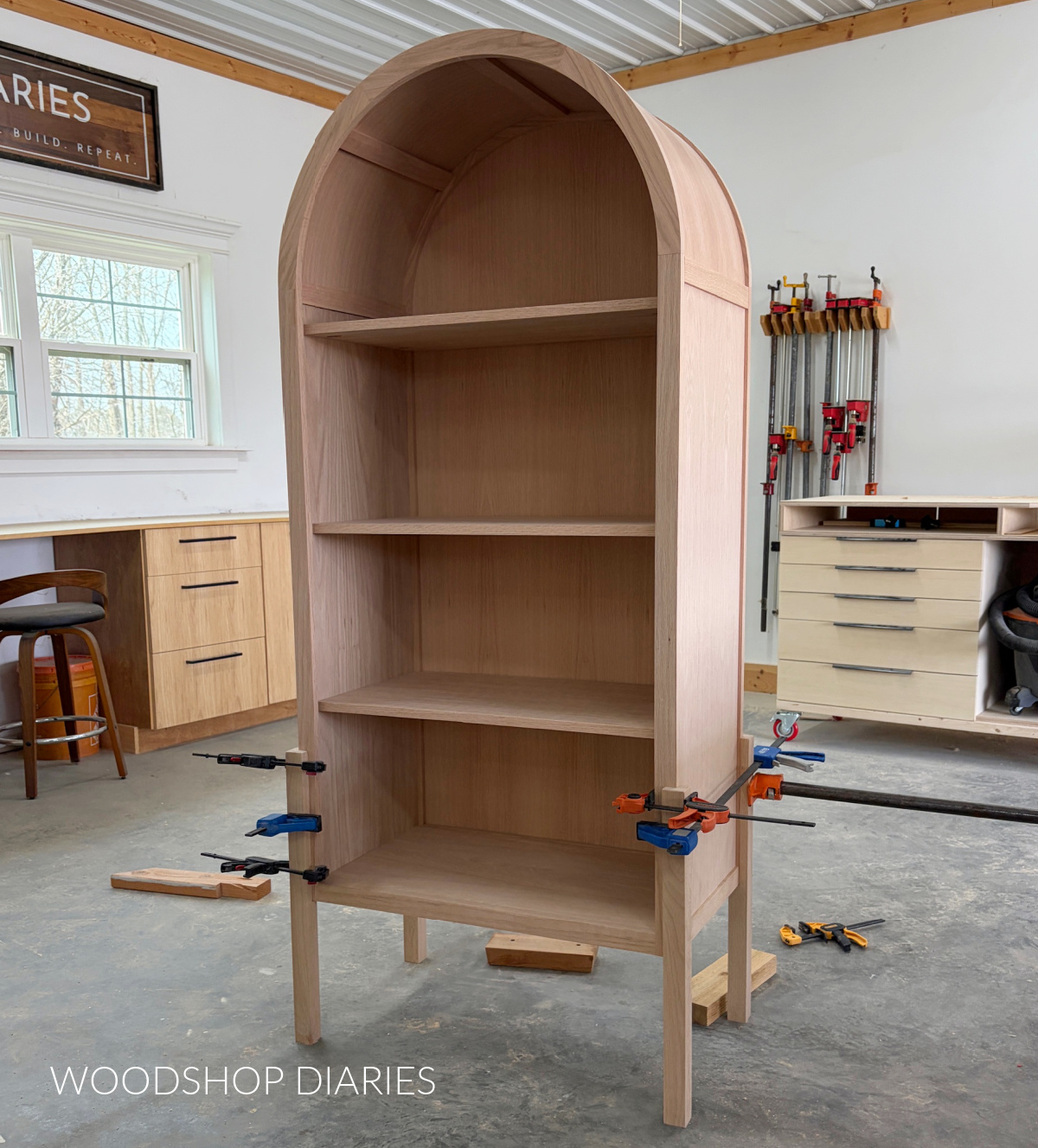 Notched legs glued and clamped around corners of arched cabinet box with shelves